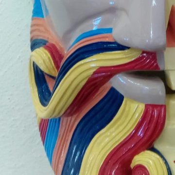 Acercamiento a una barba tallada en ondas pintadas de rojo, amarillo, azul marino, celeste y salmón