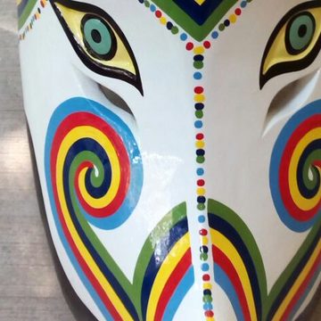 Acercamiento a la máscara de coyote: franjas azul, roja, amarilla y verde que forman una V y espirales en las mejillas