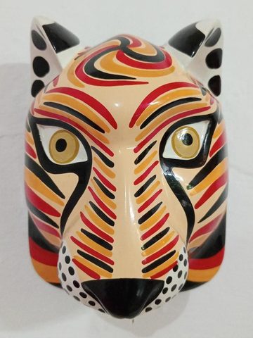 Máscara de lince de frente, color claro con franjas rojas, anaranjadas y negras, ojos color miel y manchas negras en orejas y hocico